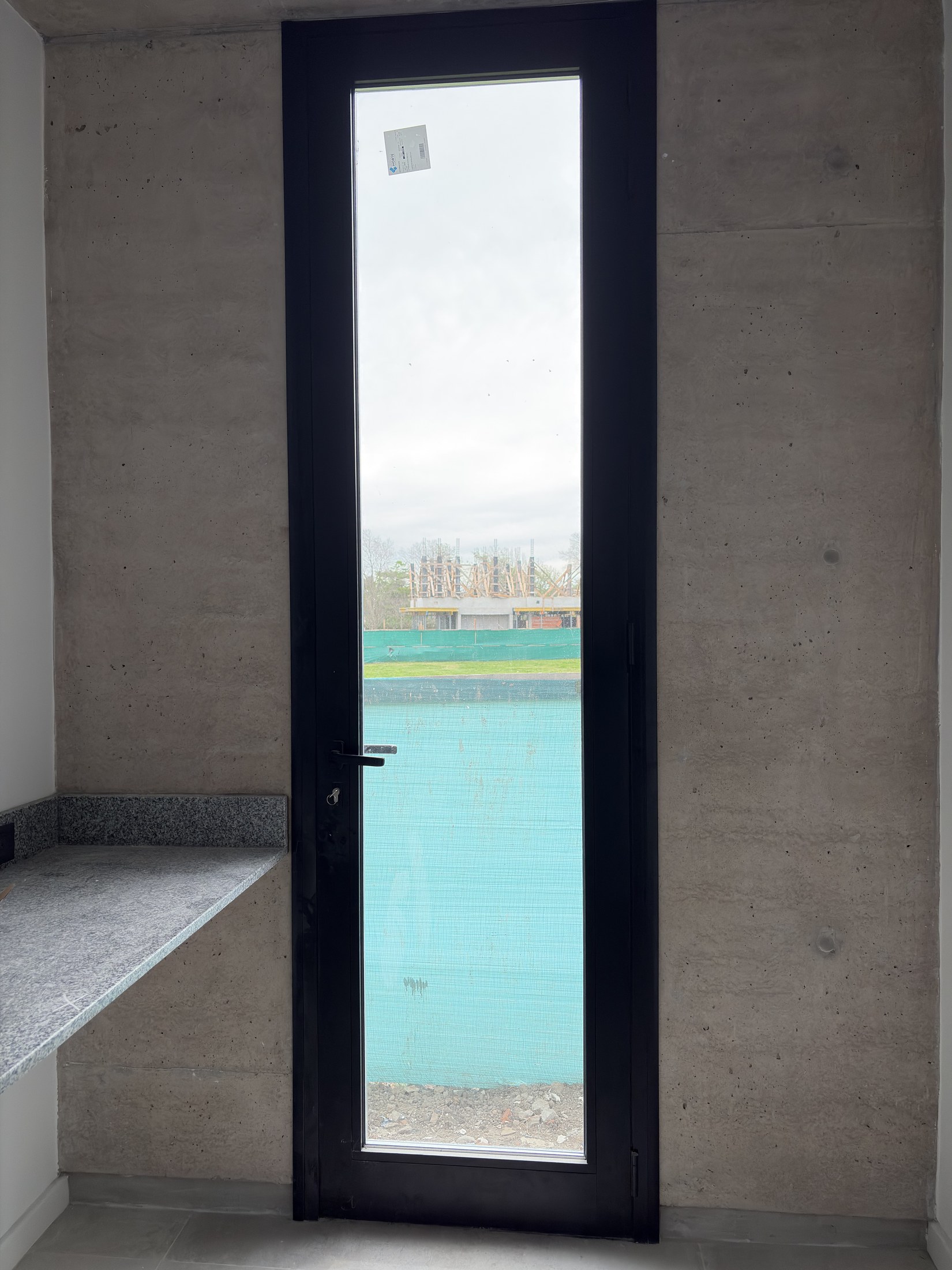 Puerta vidriada de aluminio negro en Cardos 76