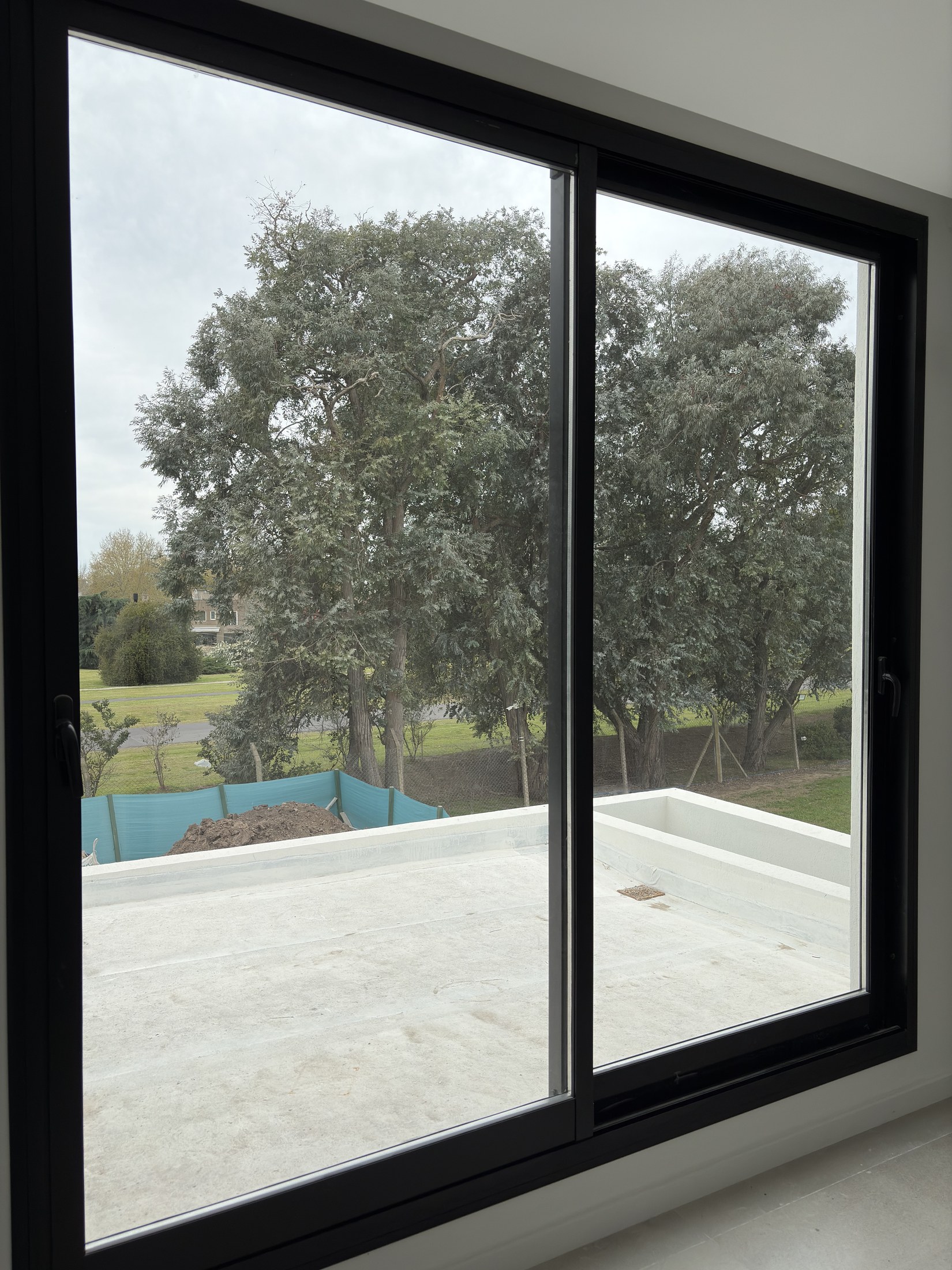 Ventanal de aluminio negro con vista al jardín en Cardos 76