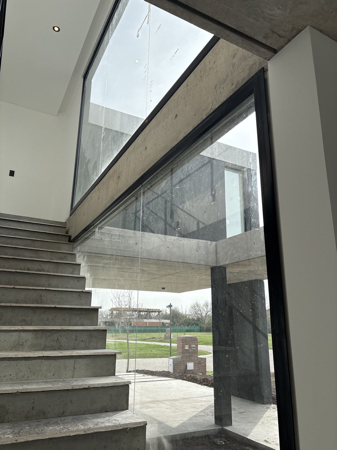 Paños de vidrio de gran formato junto a una escalera en la obra residencial Cardos 145